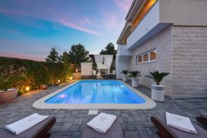 a swimming pool in the backyard of a house at My Dalmatia - Sea view Villa Bella with private heated pool and jacuzzi in Kokić