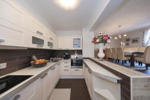a kitchen with white cabinets and a dining room at My Dalmatia - Sea view Villa Bella with private heated pool and jacuzzi in Kokić