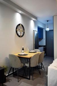 a dining room table with chairs and a clock on the wall at EmmeleiaLuxuryStudio in Xanthi