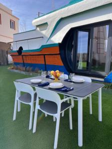 a white table with two chairs and a boat at Barco - casa con jardín privado frente al mar in Mareny Barraquetas