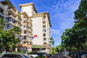 a tall white building with cars parked in a parking lot at Holiday Inn Express Haikou West Coast by IHG in Haikou