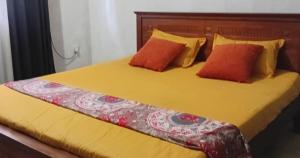 Una cama amarilla con dos almohadas naranjas encima. en S And K Holiday Stay, en Beruwala 5 fotos más