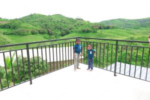 two young boys standing on a balcony with mountains in the background at Dreams Holidays Vagamon in Vagamon