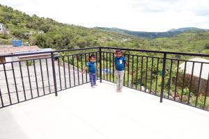 two young boys standing on a balcony with mountains in the background at Dreams Holidays Vagamon in Vagamon