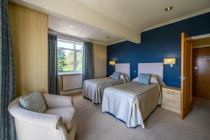 a hotel room with two beds and a chair at Trefeddian Hotel in Aberdyfi +33 photos