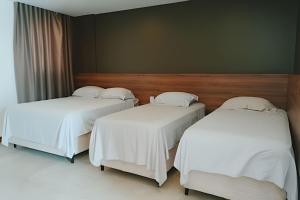 zwei Betten in einem Hotelzimmer mit weißen Laken in der Unterkunft Waua BSM| 6 suítes, Piscina, hidro, sala de jogos, in Barra de São Miguel + 30 Fotos