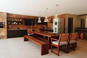 eine Küche mit einem Holztisch mit Stühlen und einem Kühlschrank in der Unterkunft Waua BSM| 6 suítes, Piscina, hidro, sala de jogos, in Barra de São Miguel