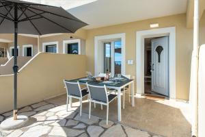 une table avec des chaises et un parasol sur une terrasse dans l'établissement Krouzeri Beach Apartments, à Nisakion