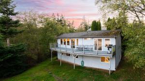 a white house with a balcony on top of it at Incredible Water Views Deck Relaxing Retreat Greenbank Getaway by AvantStay in Greenbank