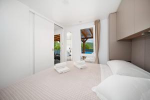 a white bedroom with two white towels on a bed at Mobile Home KAPO in Sitno Donje