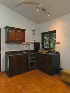a kitchen with wooden cabinets and a stove top oven at Navilehomestay in Candolim +7 photos