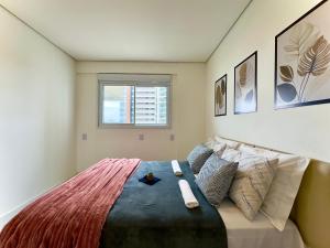 a bedroom with a large bed with pillows and a window at Apto em condomínio Pé na areia 3 Quartos Cozinha Completa Sacada com Churrasqueira Vaga de Garagem Piscina borda infinita Academia Quadra de esportes Sala de Jogos Summer Home Club acesso direto a praia in Piçarras +43 photos