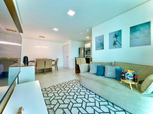 a living room with a couch and a dining room at Apto em condomínio Pé na areia 3 Quartos Cozinha Completa Sacada com Churrasqueira Vaga de Garagem Piscina borda infinita Academia Quadra de esportes Sala de Jogos Summer Home Club acesso direto a praia in Piçarras