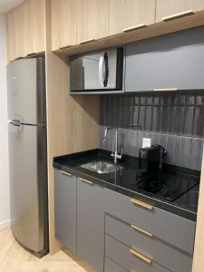 a kitchen with a sink and a refrigerator at Studio Lucas By Yoo Luxo in Porto Alegre