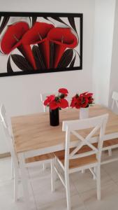 a dining room table with red flowers and a painting at Apartamento Playas de Marbella in Cartagena de Indias +6 photos