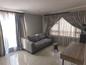 een woonkamer met een bank en grote ramen bij Nurest in Germiston