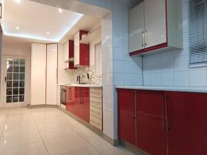 een grote keuken met rode kasten en witte apparaten bij Nurest in Germiston