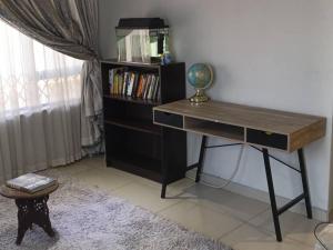 een bureau in een kamer met een boekenplank bij Nurest in Germiston