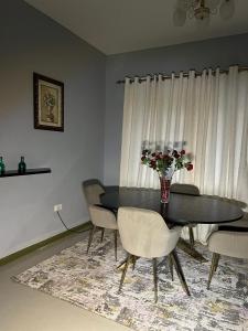 a dining room table with chairs and a vase of flowers at Napsa Complex B01 in Lusaka +8 photos