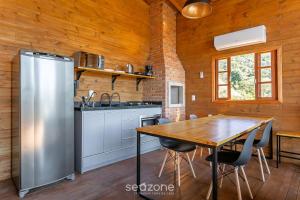 a kitchen with a table and a stainless steel refrigerator at Cabana com vista Serra Catarinense VST023 in São Paulo dos Pinhais