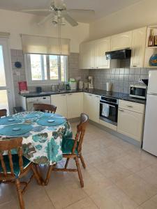 Una cocina con mesa y sillas y una cocina con gabinetes blancos. en Venus205, en Pafos