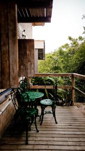 a wooden deck with two chairs and a table and chairs at Pousada Minha Rosa Paixão - PRAIA DO ROSA, SC in Imbituba