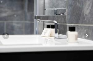 ein Waschbecken mit einem Wasserhahn und einem Spiegel in der Unterkunft The Aurelia Apartments VII - 1 Bed Apartment in Peterborough