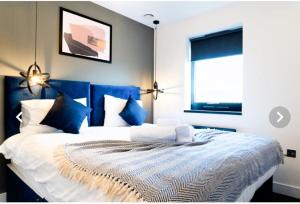 ein Schlafzimmer mit einem blauen und weißen Bett mit blauen Kissen in der Unterkunft The Aurelia Apartments VII - 1 Bed Apartment in Peterborough