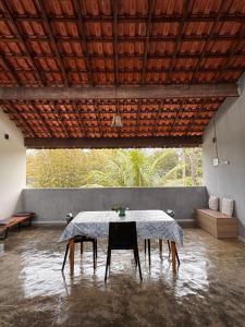 a table with chairs in a room with a large window at Chalé com Varanda Grande e Terraço Vista Mar in Itanhaém
