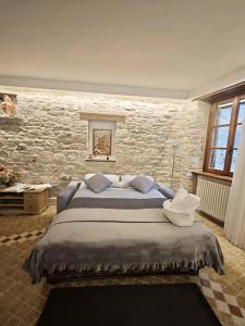 a bedroom with a large bed and a stone wall at Dimora Giada & Gloria in Gubbio