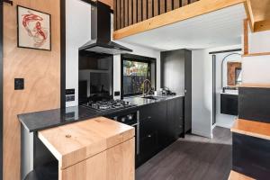 a kitchen with black cabinets and a stove top oven at Tiny Home Escape w Sauna and Plunge in Whangarei +19 photos