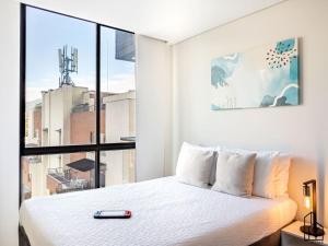 une chambre avec un lit blanc et une grande fenêtre dans l'établissement Bizsar Ocobo Aire Acondicionado Exclusivo 2 Piscinas, à Vallecito