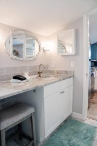 a white bathroom with a sink and a mirror at Cozy Coastal Cottages of Dunedin 4 in Dunedin