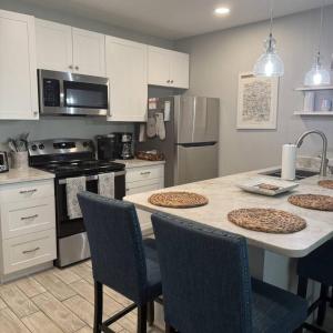 a kitchen with white cabinets and a kitchen island with chairs at Cozy Coastal Cottages of Dunedin 1 in Dunedin