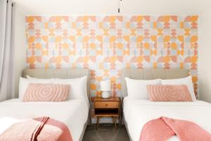 斯科茨Blush Bungalow的卧室里有两张床，床上放着粉色和橙色的枕头。 更多32张照片