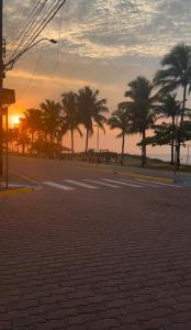 an empty street with palm trees and the sunset at Casinha beira praia Gaivota in Itanhaém