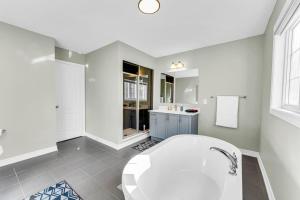 a white bathroom with a tub and a sink at Luxury Mansion with Chefs Kitchen by Niagara Falls in Thorold