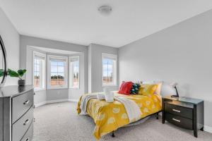 a bedroom with a bed and a dresser and windows at Cozy Home in Niagara 10 mins from Falls and Brock in Thorold