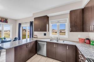 a kitchen with brown cabinets and a sink and windows at Luxury Home Mins from Waterfall next to Transit in Niagara Falls +42 photos