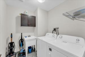 eine weiße Waschküche mit zwei Waschbecken und einer Waschmaschine in der Unterkunft Bright and Stylish Family Home Near Niagara Falls in Thorold + 53 Fotos