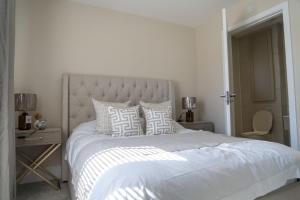a white bedroom with a large white bed with pillows at Ardlui House Gardens in High Blantyre