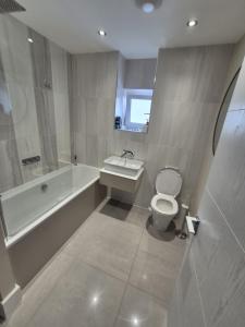a bathroom with a tub and a toilet and a sink at Ardlui House Gardens in High Blantyre
