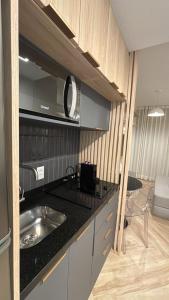 a kitchen with a sink and a microwave at Studio Lucas By Yoo Luxo in Porto Alegre
