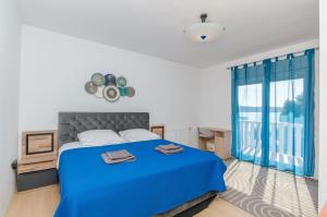 ein Schlafzimmer mit einem blauen Bett und einem großen Fenster in der Unterkunft Apartment Luxury Cream in Kaštela