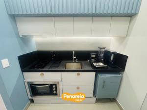 a small kitchen with a sink and a microwave at Emunah Di Città Flats Ponta de Campina in Cabedelo