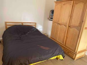 a bedroom with a bed next to a wooden cabinet at Apartment Private room in apartment in Khouribga in Khouribga