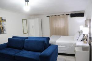 a living room with a blue couch and a bed at Optimum Stay Self Catering Accommodation - Deluxe Room in Cape Town
