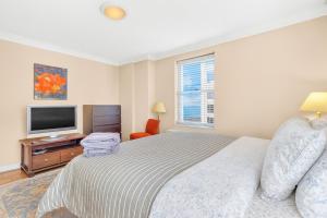 a white bedroom with a bed and a television at Downtown Atl Stay Cozy Comfort In Hotel District in Atlanta
