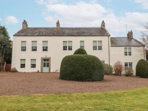 a large white house with a large bush at Cheviot Manor in Wooler