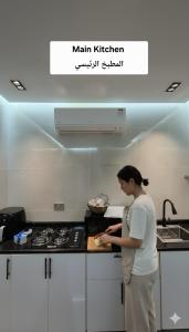 een vrouw die in een keuken staat en eten klaarmaakt bij Farmhouse-Villa--فيلا-المزرعة in Hatta